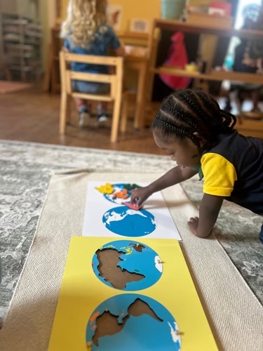 A young NIA House student working on a Montessori globe puzzle map
